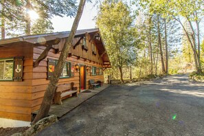 Eine Holzhütte mit Veranda, Bänken und einem gepflasterten Weg.
