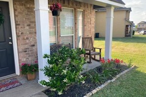 A residential house with a front porch, a brick wall, a door, a window, and a hanging planter. - 2 story retreat in Aggieland with additional parking area (College Station)