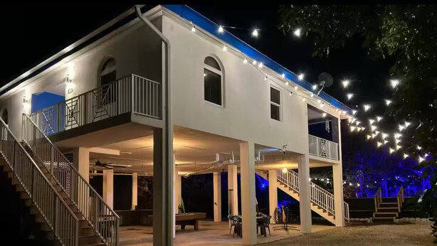 Un edificio de dos plantas con áreas de estar al aire libre, una escalera y luces colgantes.