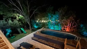 Un patio trasero con piscina, terraza de madera y zona de estar al aire libre.