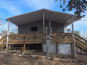 Une maison à deux étages avec une terrasse en bois, un porche couvert et un garage.