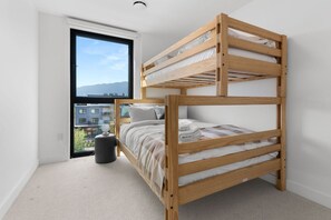 Un lit superposé dans une chambre avec vue sur les bâtiments et les montagnes, visible par la fenêtre.