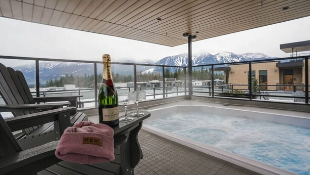 Ein Whirlpool mit Bergblick, eine Champagnerflasche und ein rosa Handtuch auf einem Tisch.