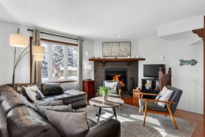 A modern living room with a fireplace, leather sofas, a television, and a sign indicating a chalet.