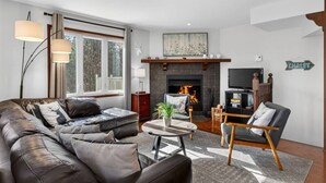 A living room with a fireplace, a sofa set, a coffee table, and a television.