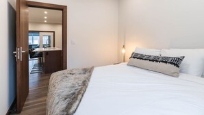 Une chambre à coucher avec un lit, un plaid en fourrure et une table de chevet avec une lampe.