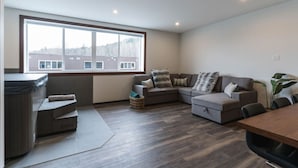 Een moderne woonkamer met een groot raam, een zithoek, een bijzettafeltje en een whirlpool.