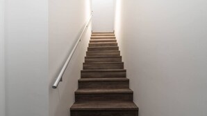 A wooden staircase with a handrail, leading to a landing. - The Alpine Den with Indoor Hot Tub (Revelstoke)