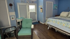 Een slaapkamer met een bed, een stoel, een plafondventilator en een raam met flessen.