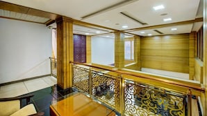 Hotelkamer met houten vloer, glazen tafel, een decoratieve balustrade en uitzicht op het interieur.