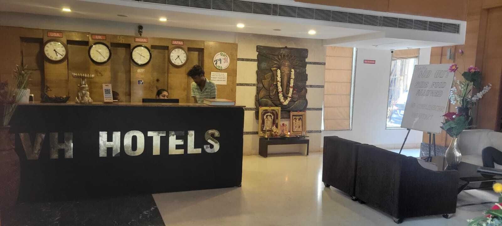 Ein Hotelrezeptionsschalter mit Uhren, die verschiedene Zeitzonen anzeigen, eine Statue und ein Schild.