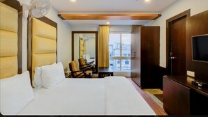 Een hotelkamer met een groot bed, een bureau, een stoel, een televisie en een raam met uitzicht op de stad.