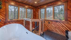 Interieur van een houten blokhut met een groot bad, houten wanden en grote ramen.
