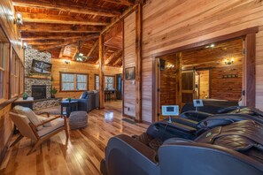 A log cabin interior with a fireplace, seating area, and massage chairs. - Cloud 9 Treehouse - Hot Tub, Private,Hocking Hills (Logan)
