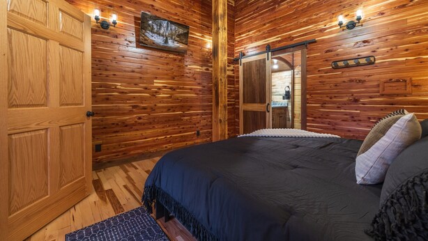 Een kamer met houten lambrisering, een bed, een deur en een spiegel.