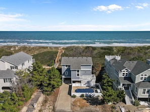 A coastal residential area with houses, a wooden walkway, and a view of the ocean.
