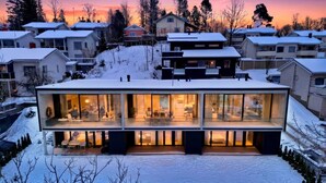 A modern house with a glass facade, surrounded by snow-covered houses. - Smart Home | Cinema | Sauna | Sonos Audio | Garage (Espoo)