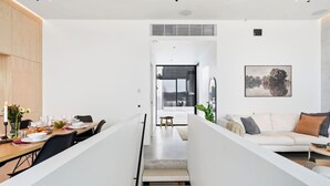A modern interior with a dining area, a sofa, and a staircase leading to an outdoor space. - Smart Home | Cinema | Sauna | Sonos Audio | Garage (Espoo)