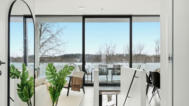 A modern interior with large windows, a sofa, chairs, and potted plants. - Smart Home | Cinema | Sauna | Sonos Audio | Garage (Espoo)