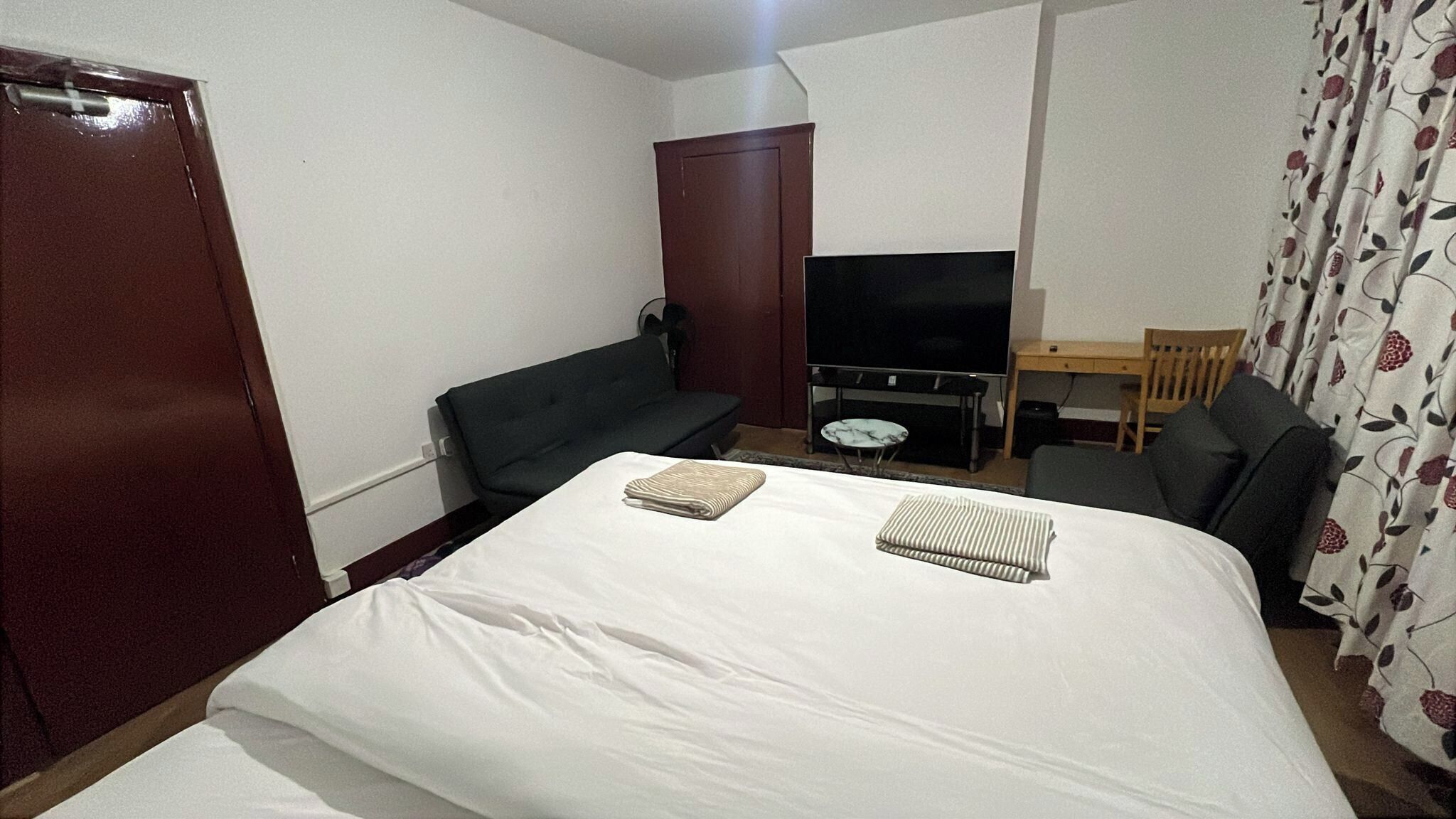 A hotel room with a bed, a television, a desk, and a chair.