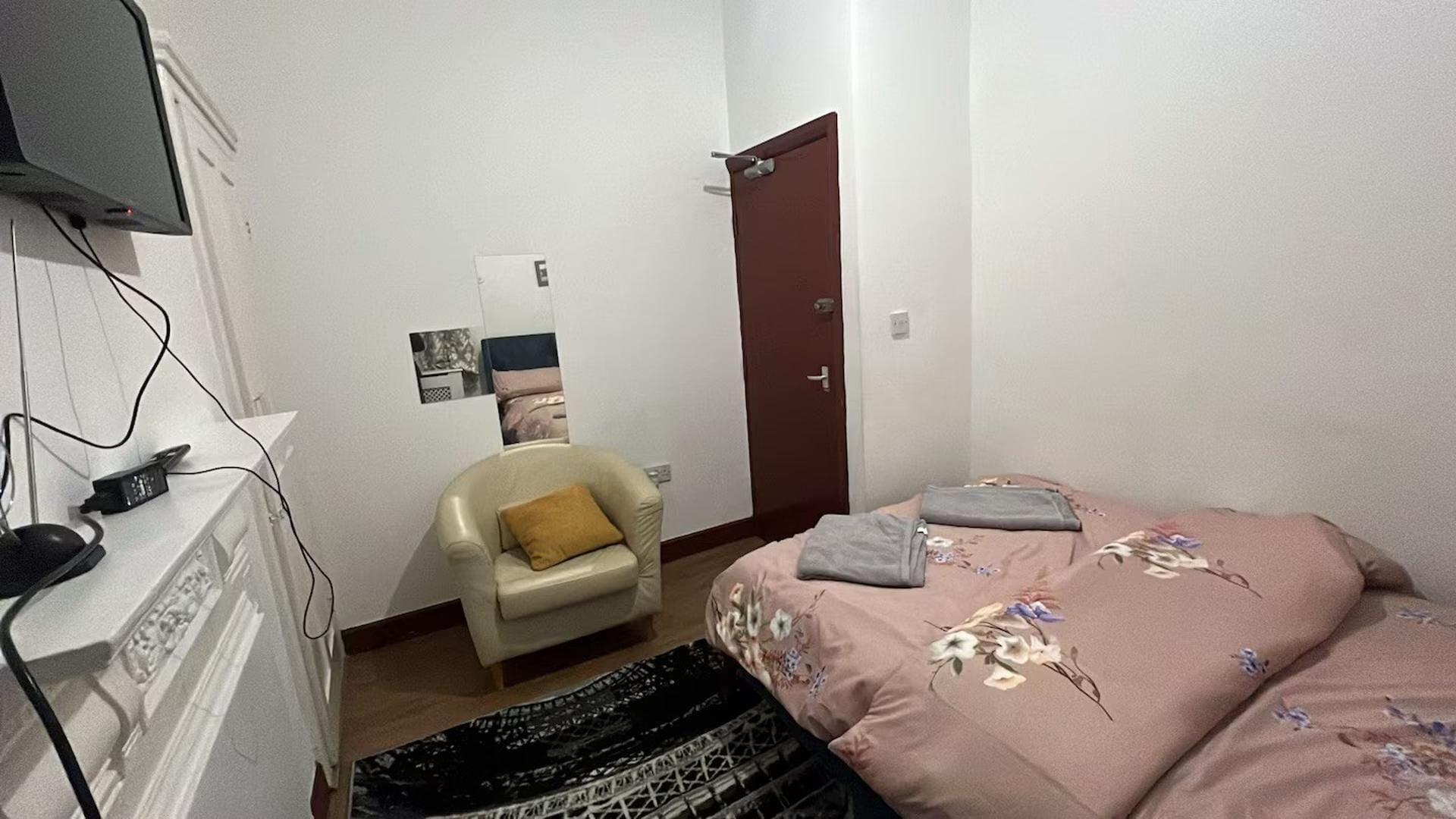 A bedroom with a bed, a chair, a desk, and a door.