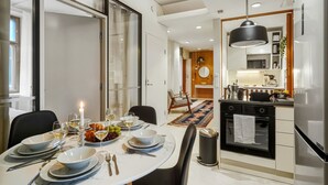 Eine moderne Küche mit Backofen, ein Essbereich mit gedecktem Tisch und ein großes Fenster.