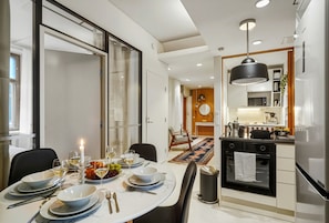 A modern kitchen with a built-in oven, a dining area with a table set for a meal, and a large window. - 4BR | City Centre | Quiet Windows | Stockmann 50m (Helsinki)