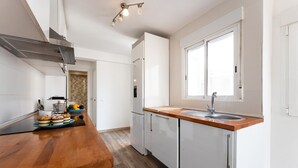 Eine moderne Küche mit weißen Schränken, einer Holzarbeitsplatte, einem eingebauten Ofen und einem Fenster.