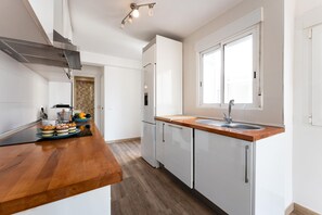 A modern kitchen with white cabinets, a wooden countertop, a built-in oven, and a window. - Apartment in the Historic Centre of Malaga (Málaga)