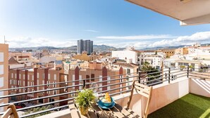 Ein Balkon mit Blick auf eine Stadtlandschaft, einschließlich Gebäude und Berge.
