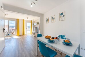 A modern dining area with a white table, blue chairs, and a view through an open door. - Apartment in the Historic Centre of Malaga (Málaga)