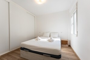 A small, clean, and well-lit bedroom with a bed, pillows, and a wooden nightstand. - Apartment in the Historic Centre of Malaga (Málaga)