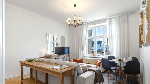 A living room with a sofa, a wooden coffee table, a TV, and a dining area with chairs and a table.