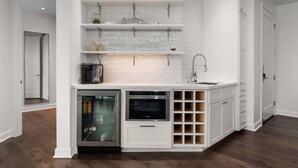 Eine moderne Küche mit weißen Schränken, einem Einbauofen und einem Weinkühlschrank.