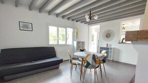 Ein stilvoller Wohnbereich mit einer Couch, einem Esstisch, Stühlen und einem Kronleuchter.