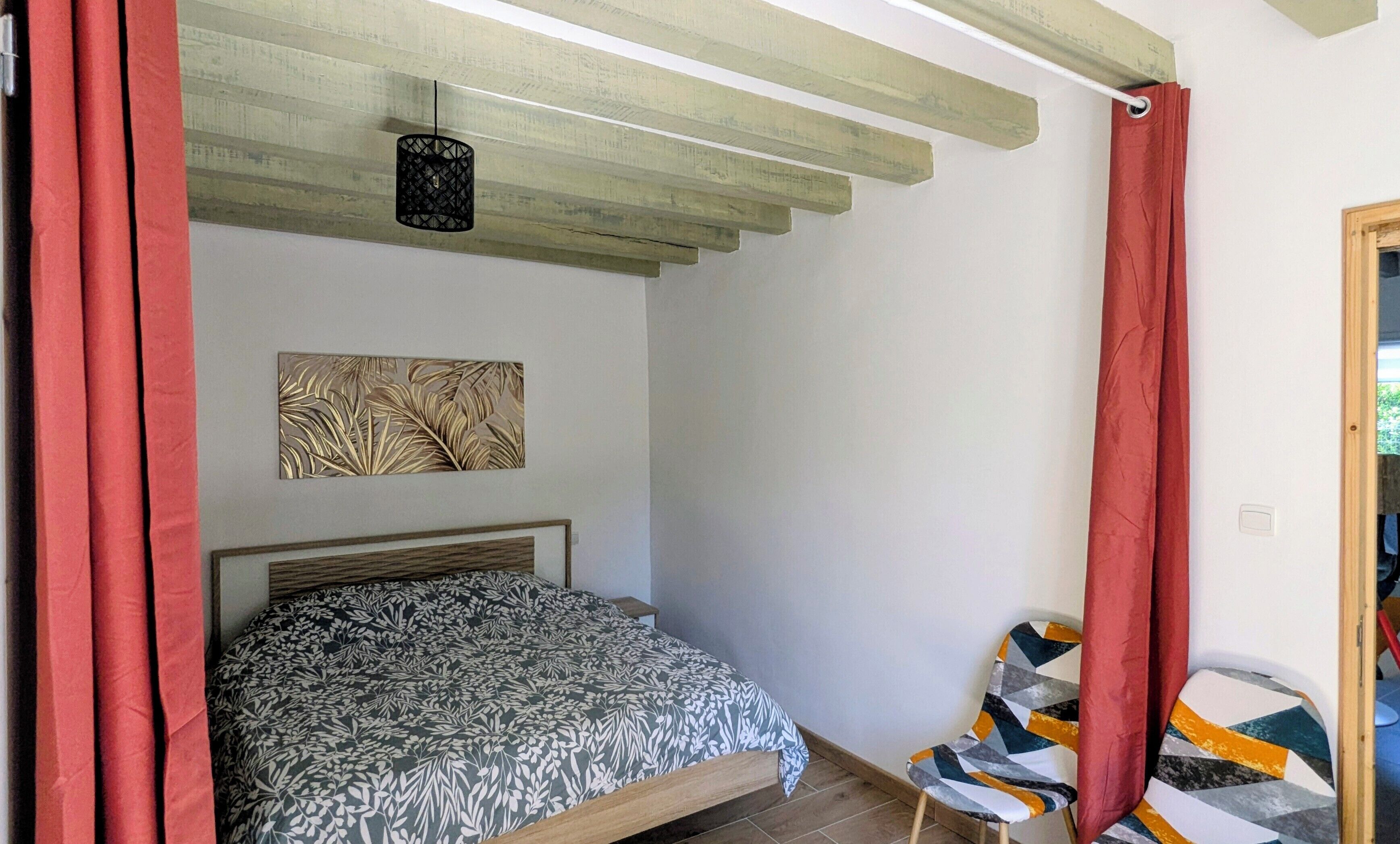 Ein Schlafzimmer mit einem Bett, einer Wandleuchte, einem Fenster und einer Tür.