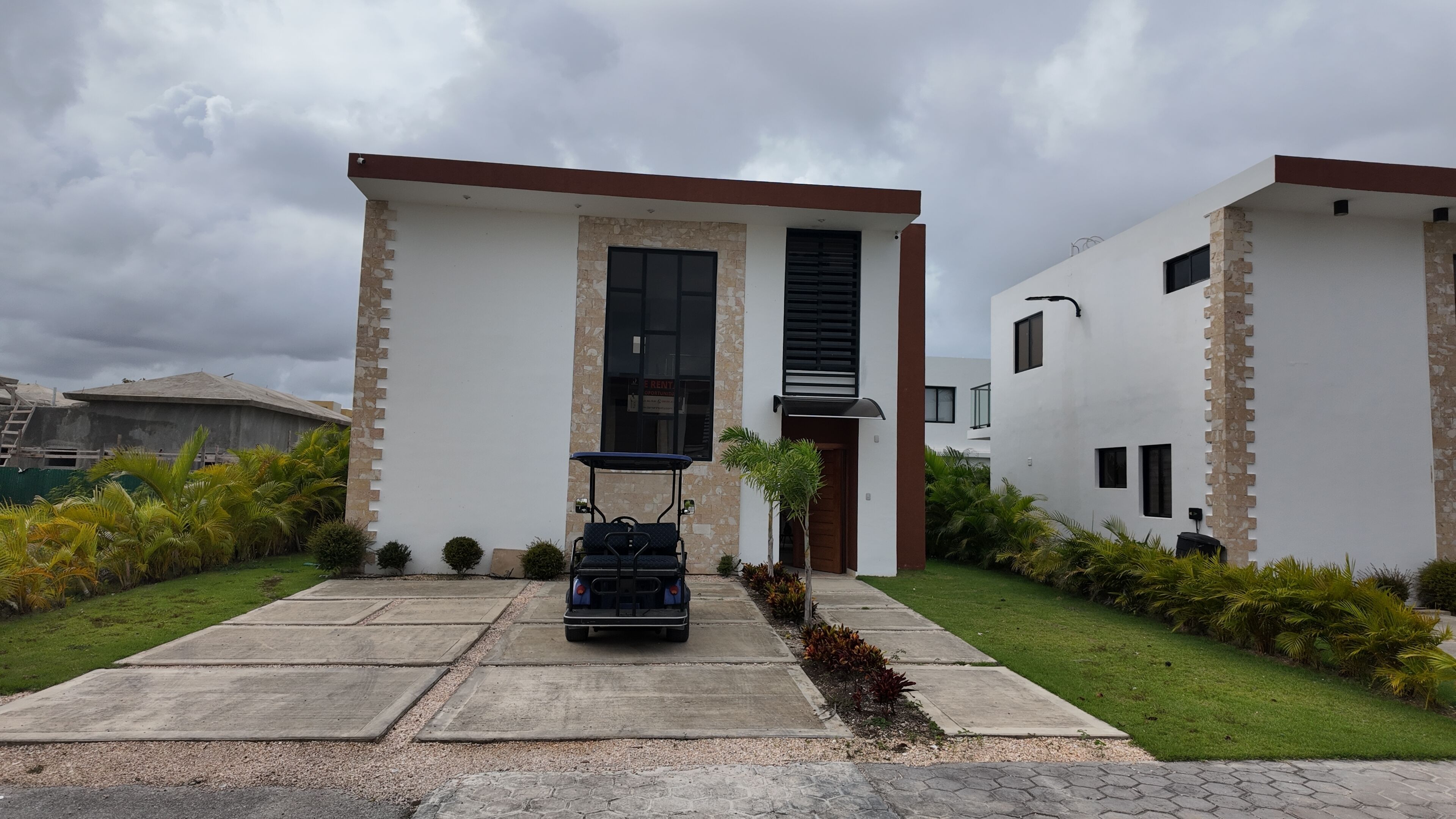 Un bâtiment moderne à deux étages, doté d’une entrée centrale, d’un petit patio agrémenté d’un chariot de golf et d’une pelouse bien entretenue.