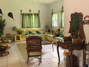 A living room with a sofa, a wooden chair, a table, and a mirror. - Las Veraneras Resort - 5 bedroom Ranch, 24 guests, Ideal for Family Reunions (Punta Remedios Los Cobanos)