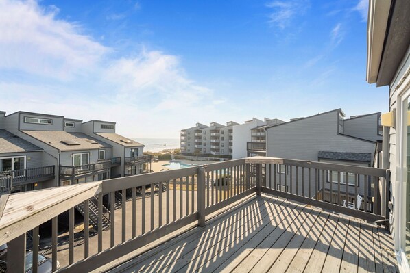 Eine Holzterrasse mit Blick auf einen Swimmingpool und angrenzende Gebäude.