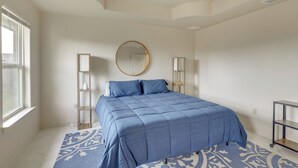 Une chambre à coucher avec un lit, un ventilateur de plafond, une fenêtre et un tapis à motifs.