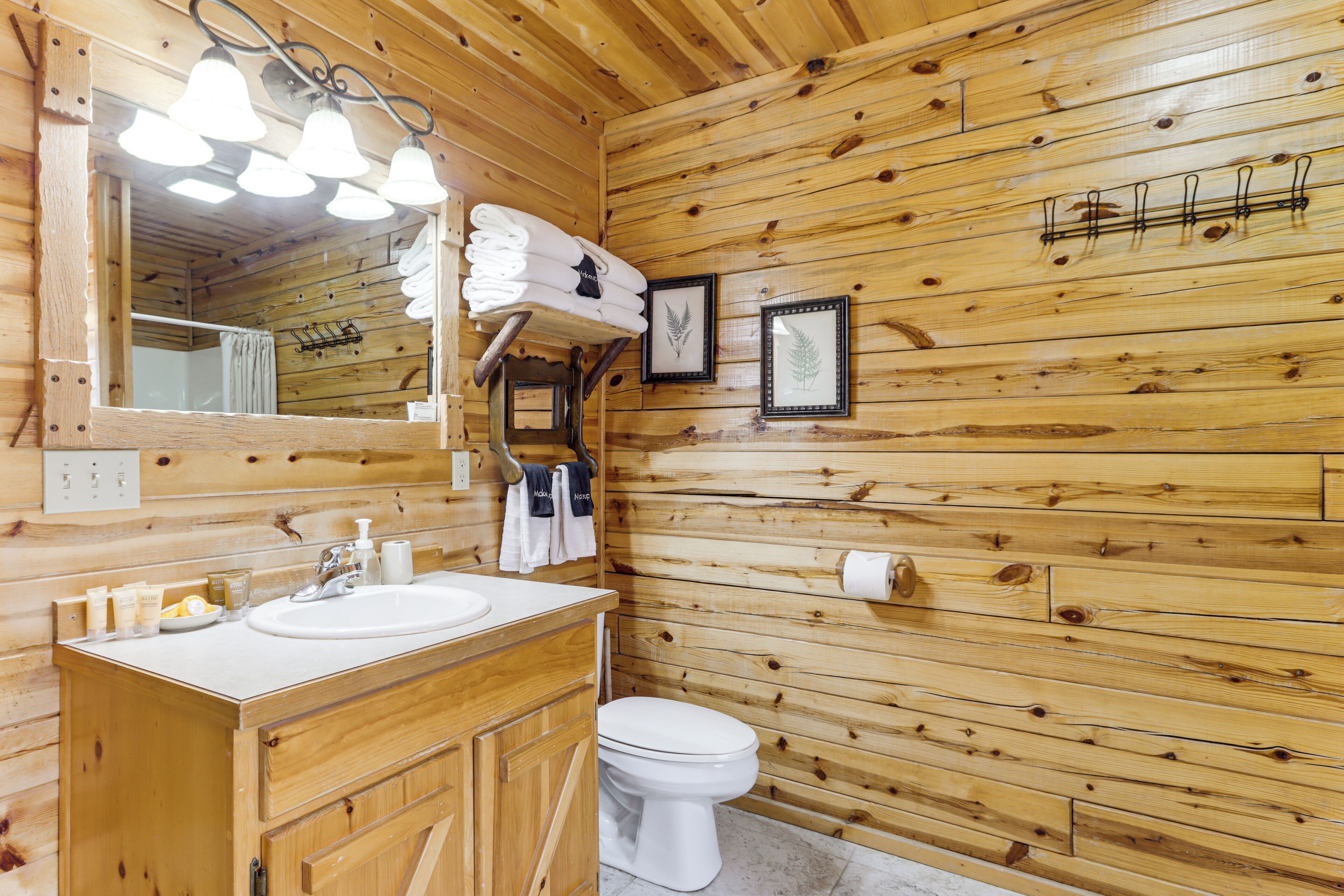 A wooden cabin-style bathroom with a sink, mirror, and toilet.