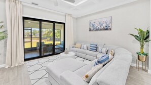 A modern living room with a grey sofa, a round coffee table, and a ceiling fan. - Family-Friendly Palm Bay Getaway! 20 Mi to Beaches (Palm Bay)