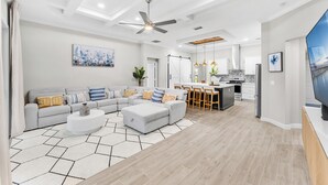 A modern living room with a sectional sofa, a coffee table, and a dining area with a kitchen in the background. - Family-Friendly Palm Bay Getaway! 20 Mi to Beaches (Palm Bay)