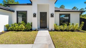 A modern single-story house with a front entrance, a concrete pathway, and well-maintained landscaping. - Family-Friendly Palm Bay Getaway! 20 Mi to Beaches (Palm Bay)