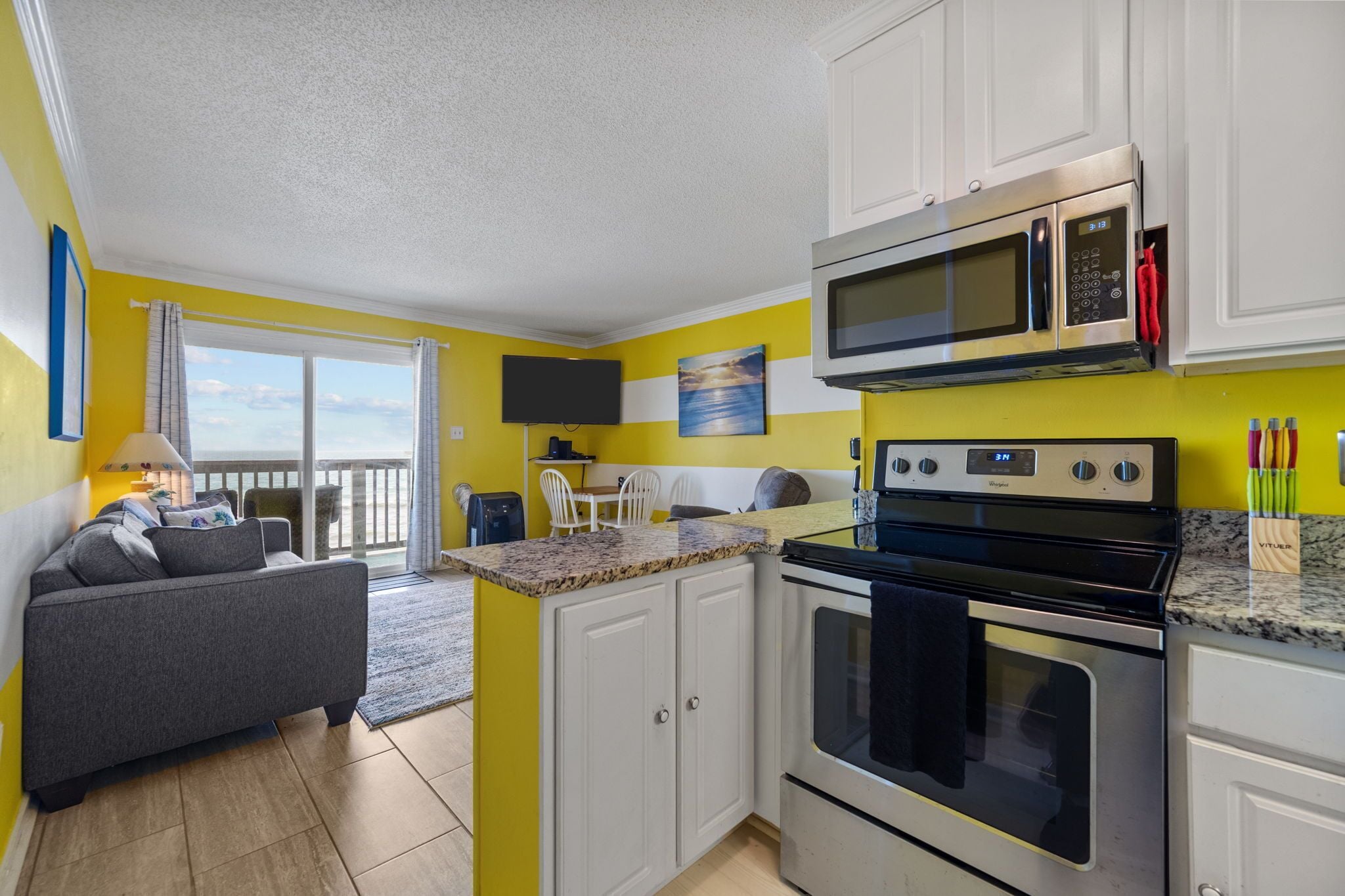A compact kitchen with white cabinets, a microwave, an oven, and a granite countertop.