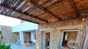 Un edificio de piedra con techo de madera, mesas al aire libre y una pared de piedra.