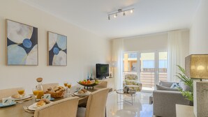 A modern dining area with a breakfast setup, a flat-screen TV, and a view of the outdoors. - #356 Vale de Parra | Pool & Nature (Albufeira)