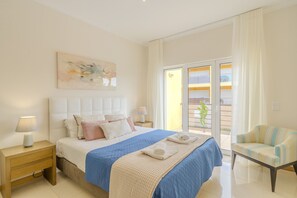 A bedroom with a bed, nightstands, a chair, a balcony, and a painting. - #356 Vale de Parra | Pool & Nature (Albufeira)