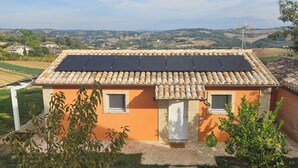 Uma casa com telhado em telhas, parede de tijolos e uma pequena janela.