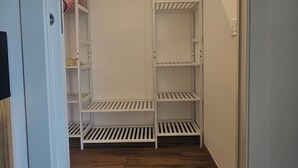 Um closet espaçoso com prateleiras brancas e piso de madeira.